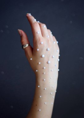 Gri arkaplanda inci kolyeli bir kadın resmi.