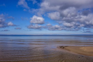 Sakin denizin üzerinde hafif kabarık bulutlar
