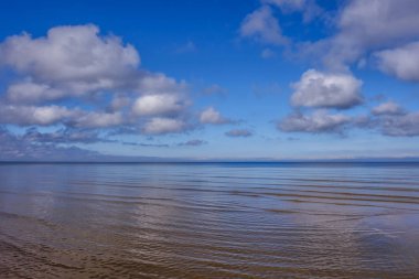Sakin denizin üzerinde hafif kabarık bulutlar