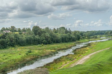 Bulutlu bir yaz gününde bir nehrin manzarası.