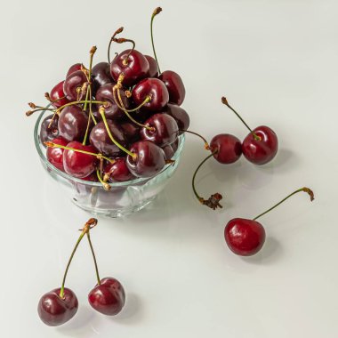 Parlak bir yüzeyde cam bir kasede tatlı kirazlar