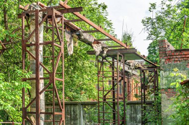Terk edilmiş sanayi bölgesi, beton çitin arkasındaki eski tuğla fabrikası ve ana ısıtıcının paslı destekleri.