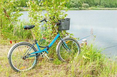 Gölün yakınındaki çimlerin üzerinde balıkçı bisikleti.