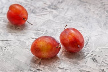 Sert bir yüzeyde üç olgun kırmızı eriğin durgun yaşamı