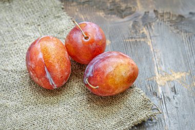 Bir çuval kumaşın üzerinde üç olgun kırmızı eriğin hayatı