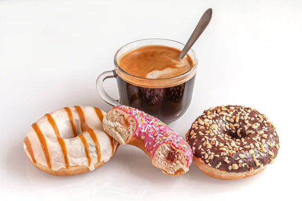 Taze pişmiş çikolata, karamel ve çilekli çörek ve beyaz cam bir yüzey üzerinde bir fincan kahve.