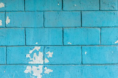 Eski tuğla bir duvarın soyut arkaplanı turkuazla boyanmış. Yakın plan.