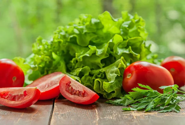 Taze çıtır marul ve sulu olgun erik domatesleri ahşap bir masada pencereye yakın.