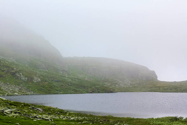 Big rocks and cliffs with fog and clouds on Veslehdn Veslehorn mountain in Hemsedal Norway.