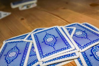 Durak oynarken ahşap masada mavi iskambil kartları.