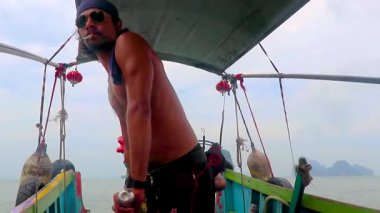 Takua Thung Phang Nga Thailand 12. June 2018 Captain ship worker tourists ad people on longtail boat ship green water limestone rocks cliffs mountains at James Bond Island Khao Phing Kan in Thailand.