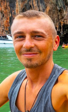 Handsome man tourist with canoe in cave turquoise water and with limestone rocks on Koh Ko Hong Island in Krasom Amphoe Takua Thung District Phang Nga Province Southern Thailand.