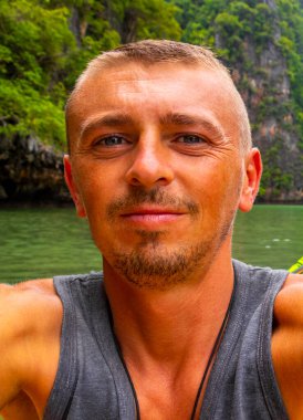 Handsome man tourist with canoe in cave turquoise water and with limestone rocks on Koh Ko Hong Island in Krasom Amphoe Takua Thung District Phang Nga Province Southern Thailand.