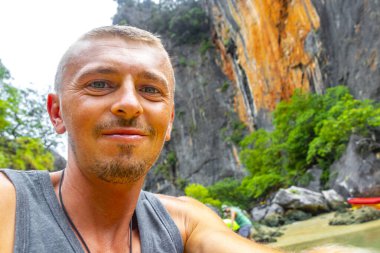 Handsome man tourist with canoe in cave turquoise water and with limestone rocks on Koh Ko Hong Island in Krasom Amphoe Takua Thung District Phang Nga Province Southern Thailand.