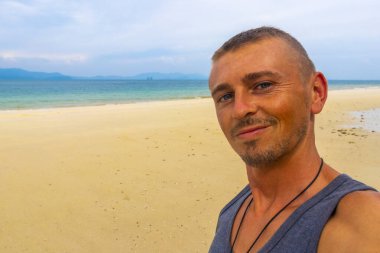 Güneydoğu Asya 'da Krasom Takua Thung Phang Nga Tayland' daki Koh Ko Na Khae Adası 'nda beyaz kum turkuvaz suyu ve palmiye ağaçları olan tropik bir plajda yakışıklı bir erkek turist..