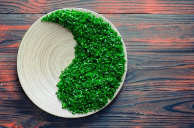 Yin yang şeklinde yeşil salata ahşap bir dokuma masasında ahşap bir tabakta