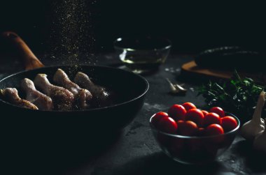 Baharat, sarımsak, otlar, kiraz domatesleri, salatalık ve sebze yağı serpiştirilmiş tavuk butları.