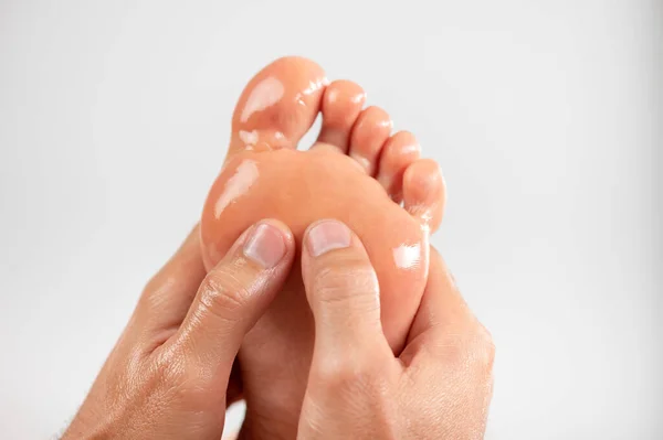 マッサージオイルで汚れた足のパッドをマッサージするのにマッサージ師は指を使う 非常にクローズアップ 光の均一な背景 — ストック写真