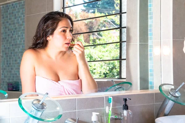 本物の女が鏡の前で口紅で唇を塗り化粧をしてる若い女性 女性の自然美と化粧品の概念 — ストック写真