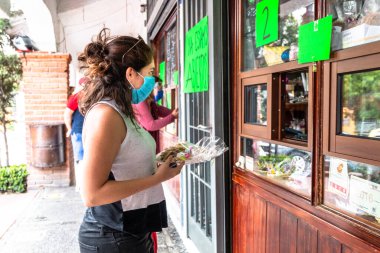 Alvaro Obregon, CDMX. Mexico. June 10, 2020. Woman buys cookies with surgical mask for the new normal. Covid 19 clipart
