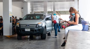 Cancun. Quintanaroo, Meksika. 08.17.2020 Kiralık bir arabanın kendisine teslim edilmesini beklerken koruyucu maske takan gerçek bir kadın. Yeni normal