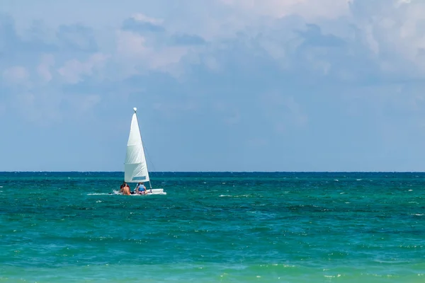 Nautical background of a white sailboat in bright sunlight, on blue ocean water, with space for text on right