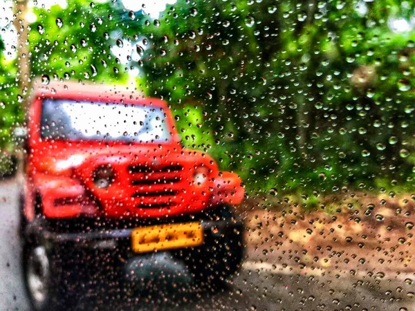 Regentropfen Auf Autoscheibe Mit Verschwommener Sicht Auf Auto Und Wald Stockbild