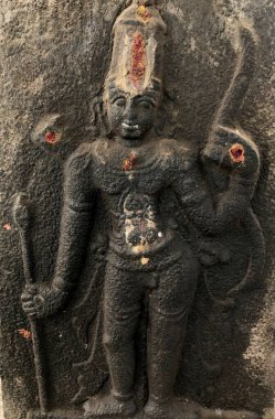 Ayaklarının altında bebek olan bir Hindu tanrısının heykeli. Shiva Tapınağı, Tamil Nadu 'nun taştan duvarlarına oyulmuş kabartma heykel.