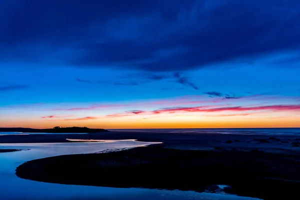 在澳大利亚湖泊入口的海面上 当美丽的色彩在太阳升起之前染红天空时 一条水路在框架的边缘形成了一个引人注目的曲线 — 图库照片