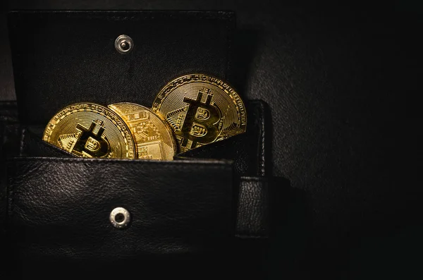 Cüzdan cryptocurrency (altın bitcoins) siyah ve koyu arka plan üzerinde shinning sikkeleri dolu. Kripto paraları cüzdana kaydedilen yığını. Cryptocurrencies metal paralar karanlık fotoğraf (yakın).