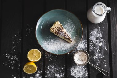 Limon, süt, pudra şekeri ve elek ahşap arka plan üzerinde çikolata cheescake fotoğraf. Karanlık gıda fotoğraf tatlı ve üstten ışıklı tatlı.