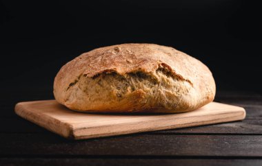 Işıklı el yapımı ekmek ahşap ve siyah arka plan üzerinde. Ev yapımı ekmek fotoğrafı kapatın.