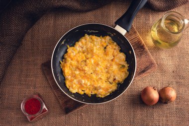 Omlet zemin kırmızı biber, soğan ve yağ yukarıda - kırsal tarzı ile fotoğraf. Jüt arka plan üzerinde siyah tavada sarı yumurta. 