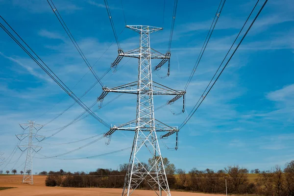 Elektrik Trafo yeni kutup, devlet ve yüksek gerilim güç hattı silueti ile mavi bulutlu gökyüzü gün batımı. Bir çok kablo ile İlkbahar alanında ışıklı iletim kulesi görünümü.