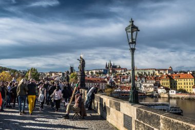 PRAG, CZECH REPUBLIC - 27 Ekim 2019: Charles Köprüsü üzerindeki Turistler ve Tüccarlar Moldova Nehri üzerindeki Hradcany Şatosu ve Saint Vitus Katedrali