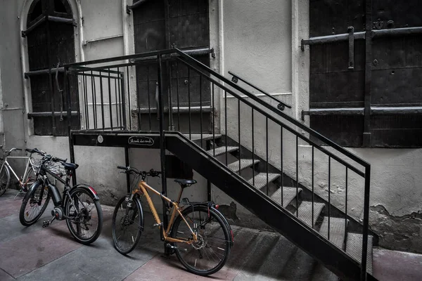 Old Bicycles Parked On Iron Stairs Beneath Historic Building With Locked Massive Doors In The Inner City Of Vienna In Austria