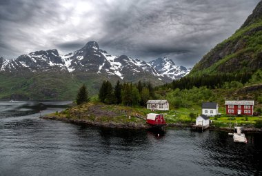 Norveç 'teki Lofoten' de, Trollfjord yakınlarında küçük köylü ve karlı dağlarla kıyı manzarası
