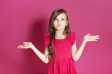 Küçük 8 yaşında kız elleri pembe tarafsız arka plan üzerinde bazı duygusal jest yapmak. O uzun esmer saç ve giyim kırmızı yazlık elbise vardır. Yüzünde komik ifade