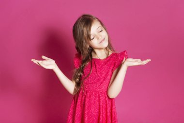 Küçük 8 yaşında kız elleri pembe tarafsız arka plan üzerinde bazı duygusal jest yapmak. O uzun esmer saç ve giyim kırmızı yazlık elbise vardır. Yüzünde komik ifade
