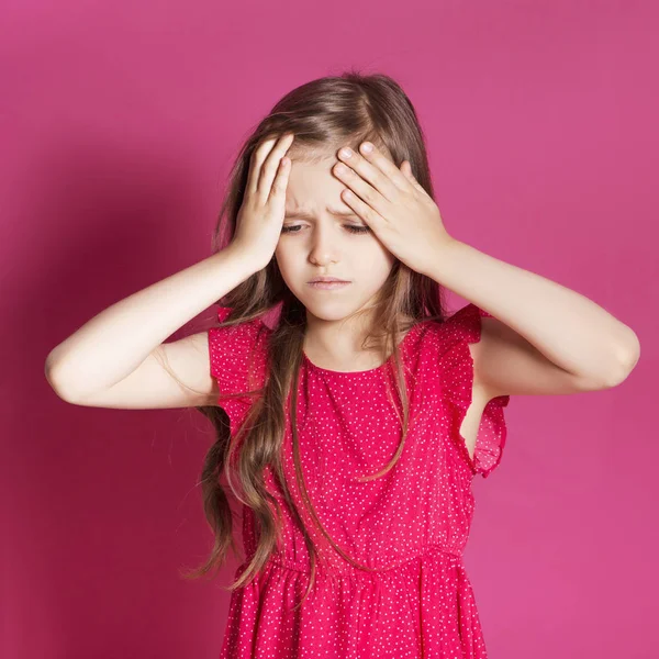 Küçük 8 yaşında kız elleri pembe tarafsız arka plan üzerinde bazı duygusal jest yapmak. O uzun esmer saç ve giyim kırmızı yazlık elbise vardır. Yüzünde komik ifade