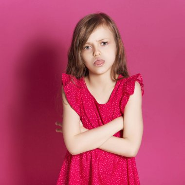 Küçük 8 yaşında kız elleri pembe tarafsız arka plan üzerinde bazı duygusal jest yapmak. O uzun esmer saç ve giyim kırmızı yazlık elbise vardır. Yüzünde komik ifade
