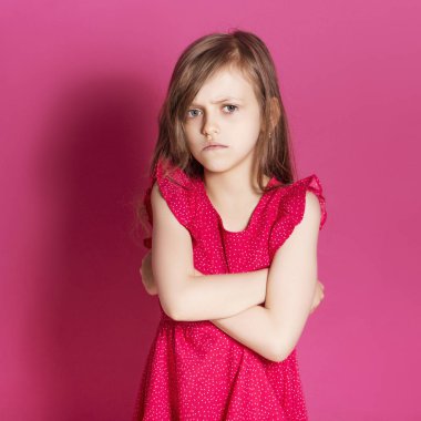 Küçük 8 yaşında kız elleri pembe tarafsız arka plan üzerinde bazı duygusal jest yapmak. O uzun esmer saç ve giyim kırmızı yazlık elbise vardır. Yüzünde komik ifade