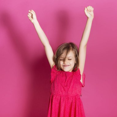 Küçük 8 yaşında kız elleri pembe tarafsız arka plan üzerinde bazı duygusal jest yapmak. O uzun esmer saç ve giyim kırmızı yazlık elbise vardır. Yüzünde komik ifade