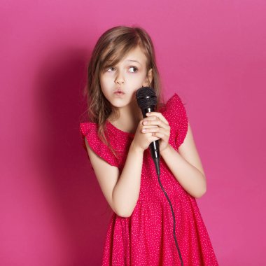 Küçük 8 yaşında kız elleri pembe tarafsız arka plan üzerinde bazı duygusal jest yapmak. O uzun esmer saç ve giyim kırmızı yazlık elbise vardır. Yüzünde komik ifade