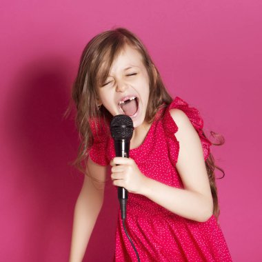 Küçük 8 yaşında kız elleri pembe tarafsız arka plan üzerinde bazı duygusal jest yapmak. O uzun esmer saç ve giyim kırmızı yazlık elbise vardır. Yüzünde komik ifade