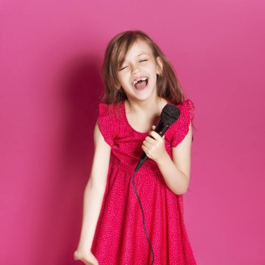 Küçük 8 yaşında kız elleri pembe tarafsız arka plan üzerinde bazı duygusal jest yapmak. O uzun esmer saç ve giyim kırmızı yazlık elbise vardır. Yüzünde komik ifade