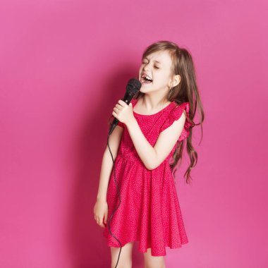 Küçük 8 yaşında kız elleri pembe tarafsız arka plan üzerinde bazı duygusal jest yapmak. O uzun esmer saç ve giyim kırmızı yazlık elbise vardır. Yüzünde komik ifade