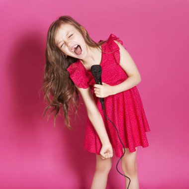 Küçük 8 yaşında kız elleri pembe tarafsız arka plan üzerinde bazı duygusal jest yapmak. O uzun esmer saç ve giyim kırmızı yazlık elbise vardır. Yüzünde komik ifade