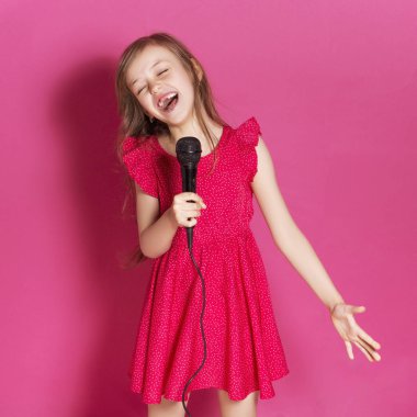 Küçük 8 yaşında kız elleri pembe tarafsız arka plan üzerinde bazı duygusal jest yapmak. O uzun esmer saç ve giyim kırmızı yazlık elbise vardır. Yüzünde komik ifade