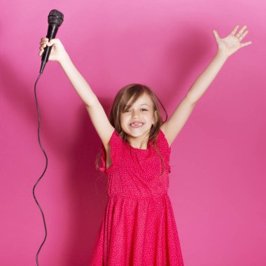 Küçük 8 yaşında kız elleri pembe tarafsız arka plan üzerinde bazı duygusal jest yapmak. O uzun esmer saç ve giyim kırmızı yazlık elbise vardır. Yüzünde komik ifade